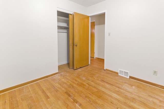 unfurnished bedroom featuring light wood-style floors, baseboards, visible vents, and a closet