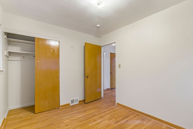 unfurnished bedroom with a closet, visible vents, baseboards, and light wood finished floors