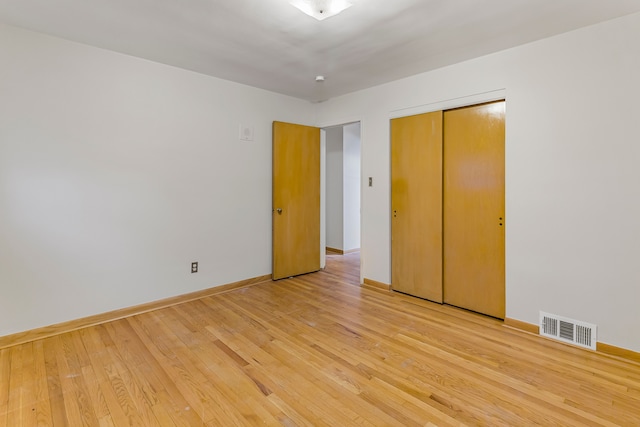 unfurnished bedroom featuring a closet, light wood-type flooring, visible vents, and baseboards