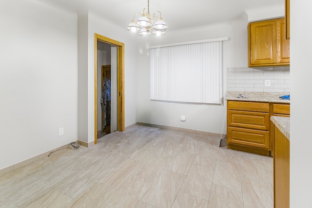 unfurnished dining area with an inviting chandelier and baseboards