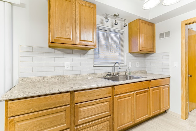 kitchen with tasteful backsplash, a sink, and visible vents