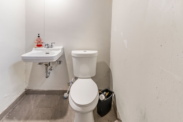 half bathroom featuring toilet, baseboards, and a sink