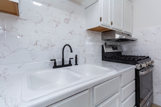 kitchen with white cabinets, gas range, light countertops, under cabinet range hood, and a sink