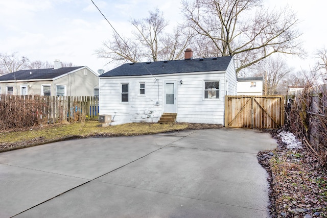 back of property with entry steps, a chimney, a gate, fence, and central AC