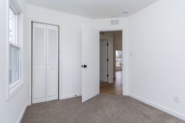 unfurnished bedroom with a closet, visible vents, baseboards, and carpet flooring