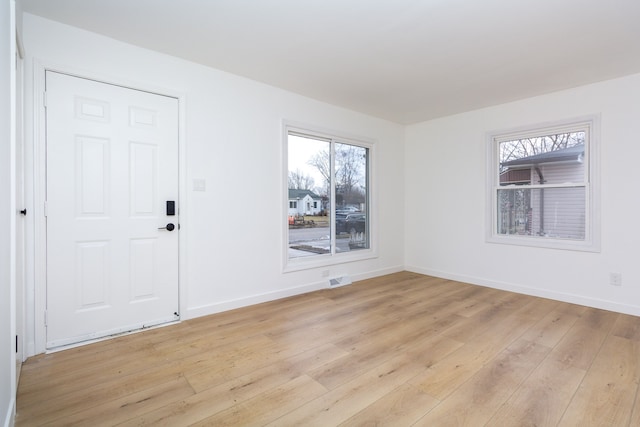 spare room with light wood-style floors, plenty of natural light, and baseboards