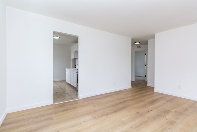 spare room with baseboards, visible vents, and light wood-style floors