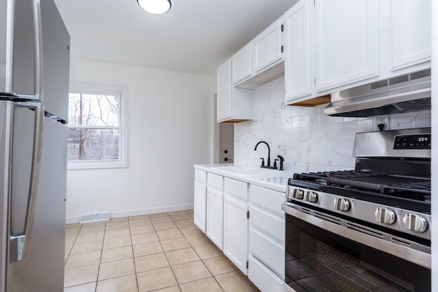 kitchen with visible vents, freestanding refrigerator, stainless steel gas stove, a sink, and under cabinet range hood