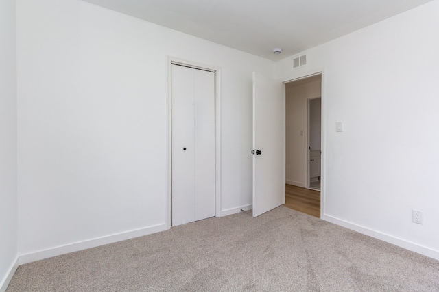 unfurnished bedroom featuring carpet floors, a closet, visible vents, and baseboards