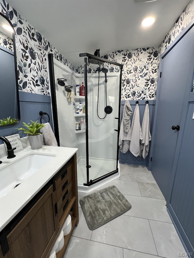 full bath with a wainscoted wall, a stall shower, vanity, and wallpapered walls