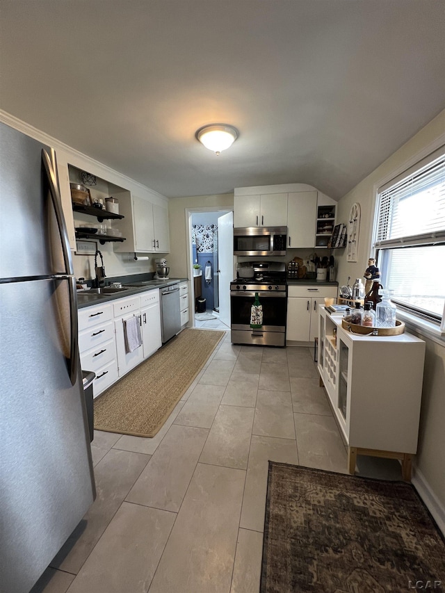 kitchen with a sink, white cabinets, appliances with stainless steel finishes, open shelves, and dark countertops