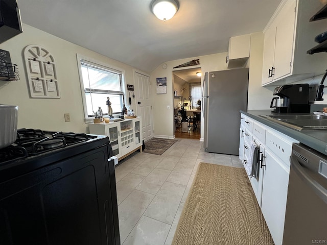 kitchen featuring stainless steel appliances, a sink, white cabinetry, vaulted ceiling, and dark countertops