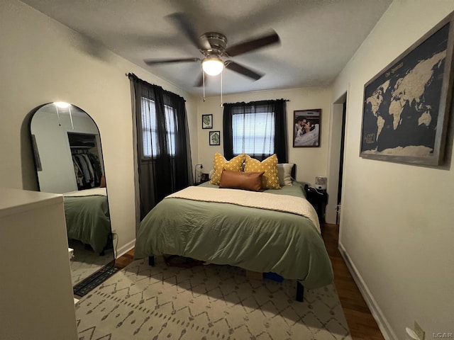 bedroom featuring a ceiling fan, baseboards, and wood finished floors