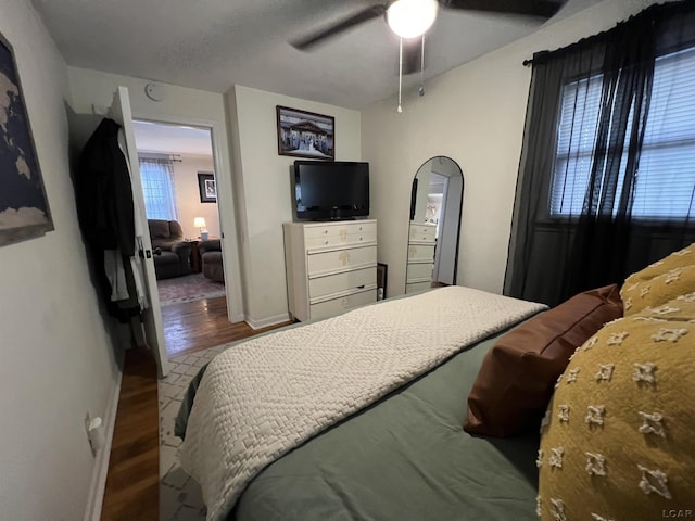 bedroom with baseboards, arched walkways, ceiling fan, and wood finished floors