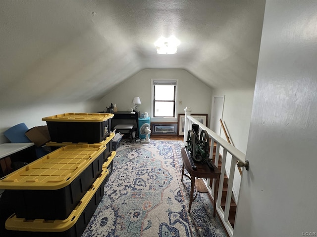 bonus room with lofted ceiling, a textured ceiling, and wood finished floors