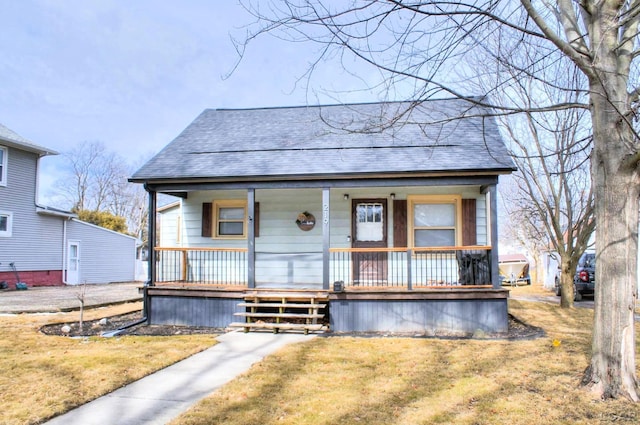 bungalow featuring a porch, roof with shingles, and a front yard