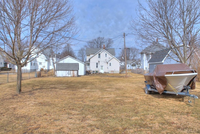 view of yard with an outbuilding, a shed, fence, and a residential view