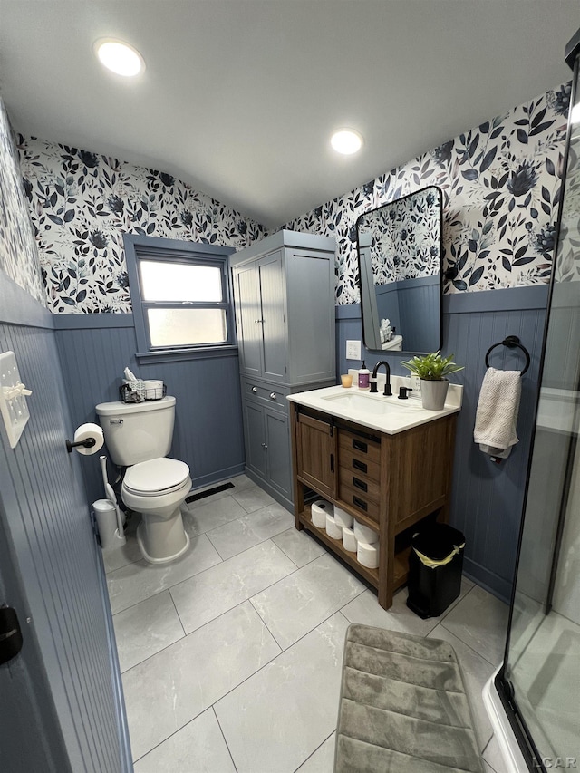 bathroom with a stall shower, a wainscoted wall, and wallpapered walls