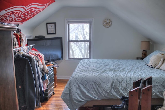 bedroom featuring baseboards, vaulted ceiling, and wood finished floors