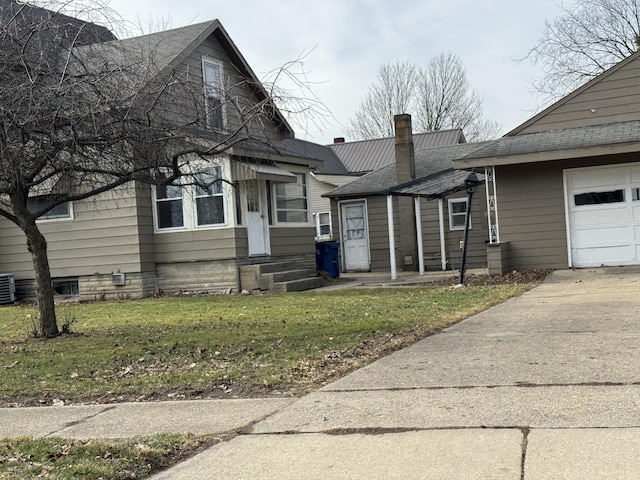 view of front of property featuring entry steps, concrete driveway, a chimney, cooling unit, and a front lawn