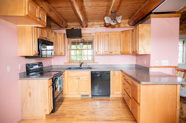 kitchen with beamed ceiling, a sink, a peninsula, and black appliances