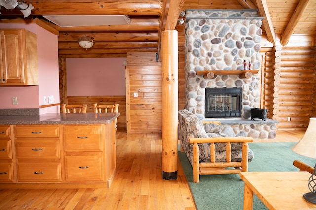 kitchen featuring a fireplace, log walls, light wood finished floors, wooden ceiling, and beamed ceiling