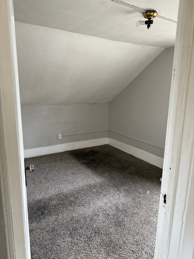 bonus room with baseboards, a textured ceiling, lofted ceiling, and carpet