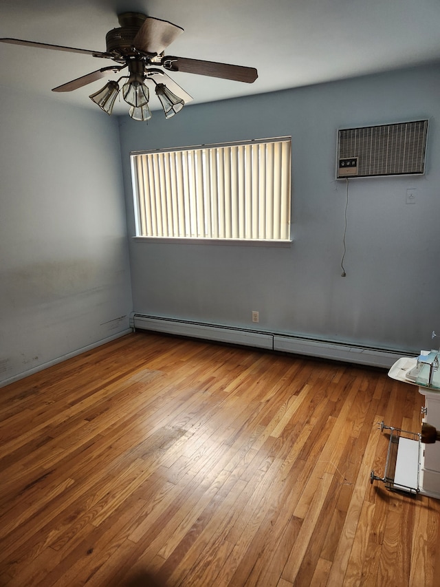 empty room with a baseboard heating unit, a wall mounted AC, hardwood / wood-style flooring, and a ceiling fan