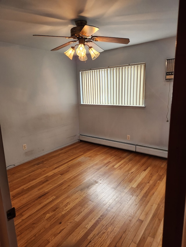 unfurnished room featuring a baseboard heating unit, ceiling fan, and wood-type flooring