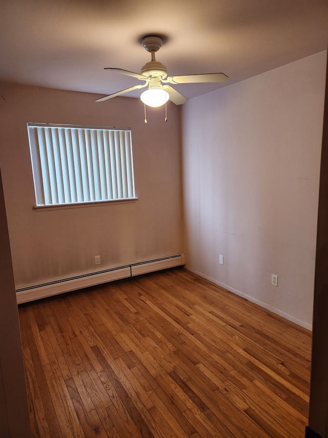 spare room with a ceiling fan, baseboards, a baseboard heating unit, and hardwood / wood-style floors