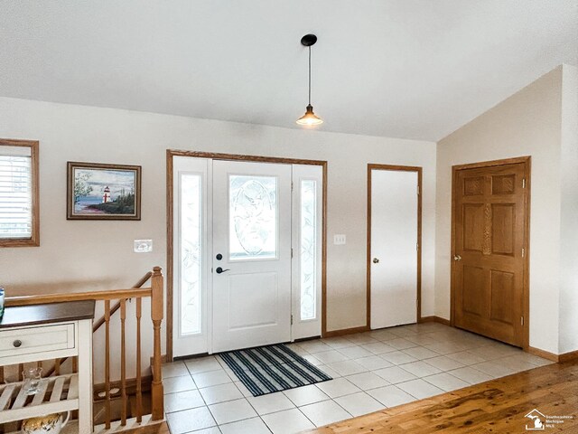 foyer featuring lofted ceiling, light tile patterned flooring, and baseboards