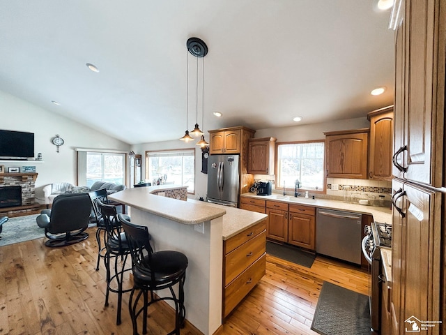 kitchen with a breakfast bar area, light countertops, appliances with stainless steel finishes, open floor plan, and a sink