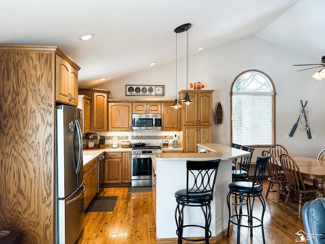 kitchen featuring lofted ceiling, a kitchen bar, stainless steel appliances, and light countertops