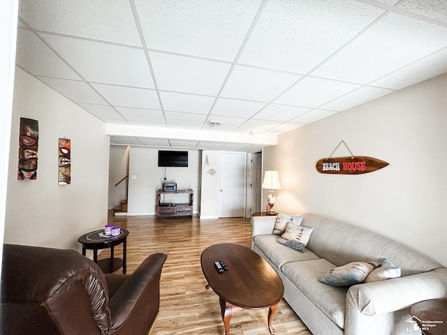 living area with stairs, wood finished floors, and a paneled ceiling