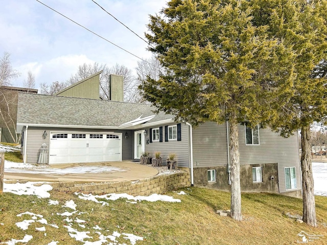 view of front facade featuring a garage, concrete driveway, a chimney, roof with shingles, and a front yard