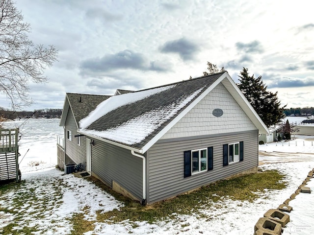 snow covered property featuring roof with shingles