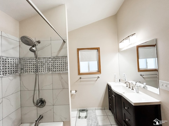 bathroom with lofted ceiling, tiled shower, and vanity