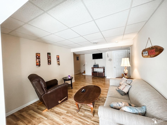 living room featuring light wood-style flooring, baseboards, and a drop ceiling