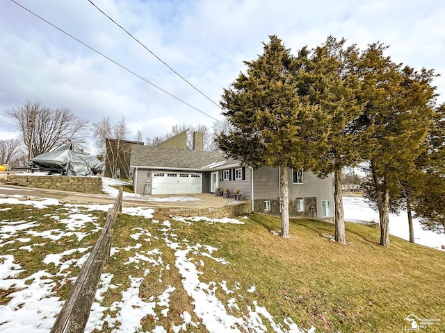 view of front of home featuring a lawn, a chimney, and an attached garage