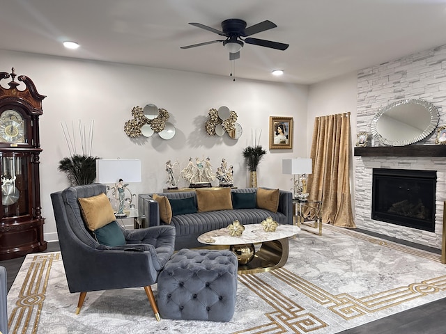 living room with a stone fireplace and a ceiling fan