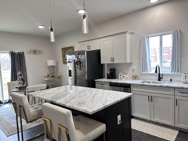 kitchen featuring stainless steel appliances, a breakfast bar area, a sink, and decorative backsplash