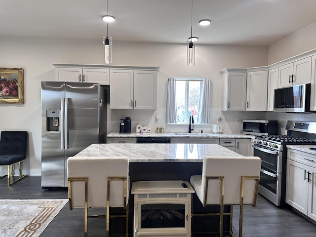 kitchen with a kitchen island, backsplash, dark wood-style flooring, stainless steel appliances, and a sink