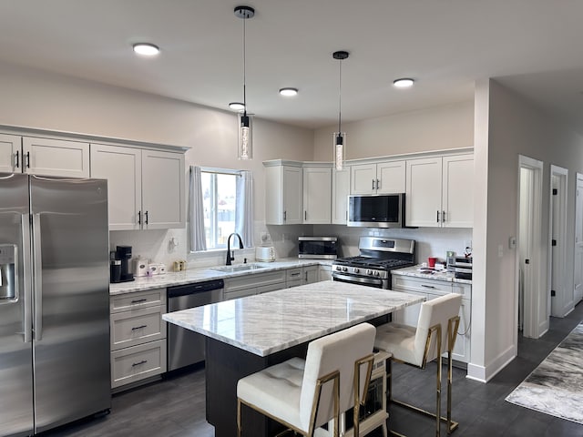 kitchen with a center island, stainless steel appliances, backsplash, a sink, and light stone countertops