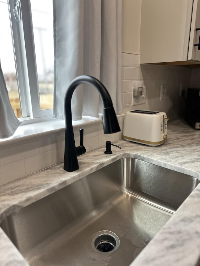 details with white cabinetry, backsplash, and a sink