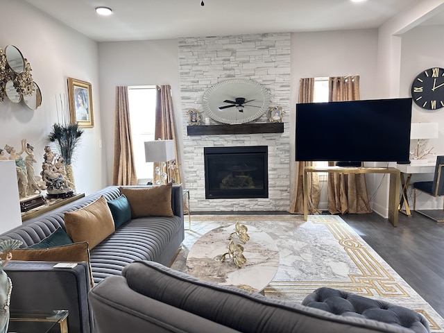 living room with a stone fireplace and wood finished floors