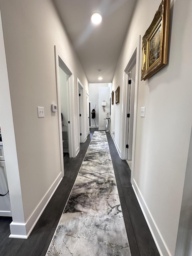 hallway featuring baseboards and dark wood-style flooring