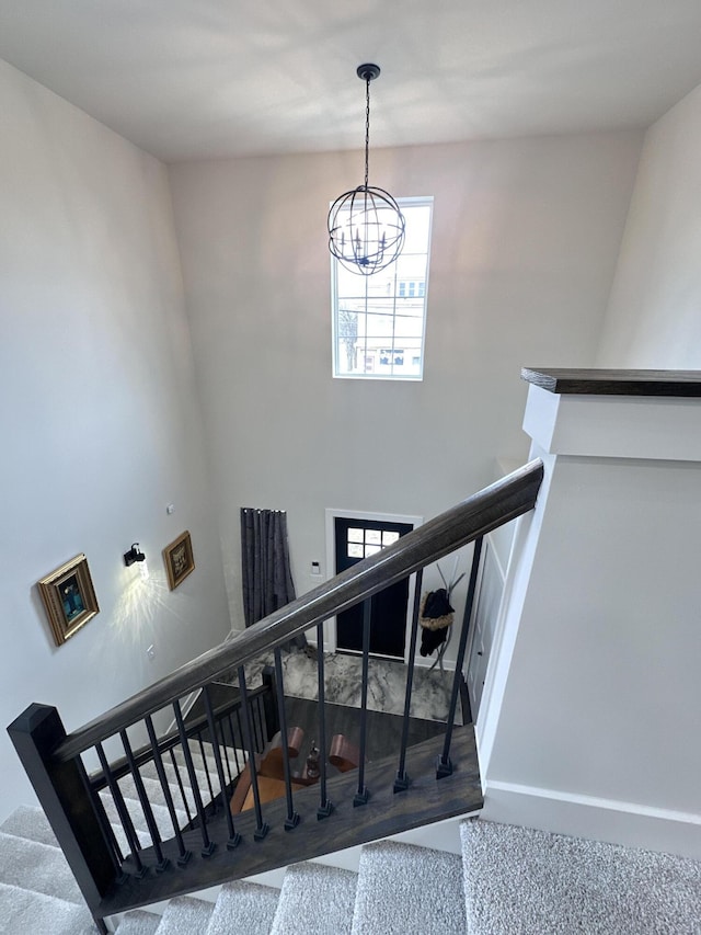 stairway featuring baseboards and an inviting chandelier