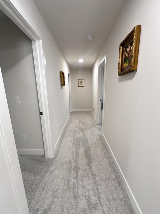 hallway featuring carpet and baseboards