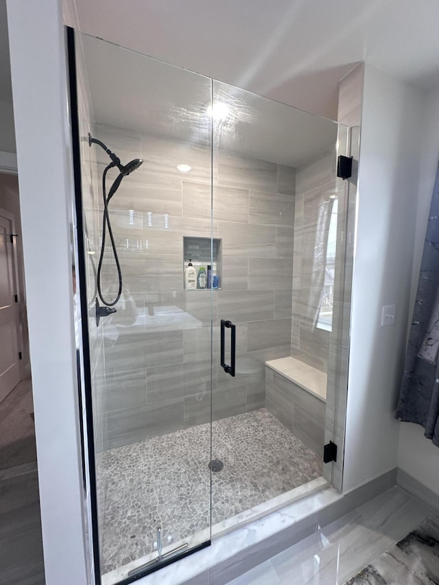 full bath with marble finish floor, a shower stall, and baseboards