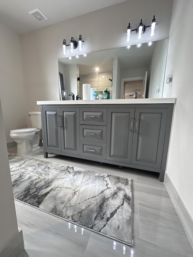 full bathroom with baseboards, visible vents, toilet, and double vanity